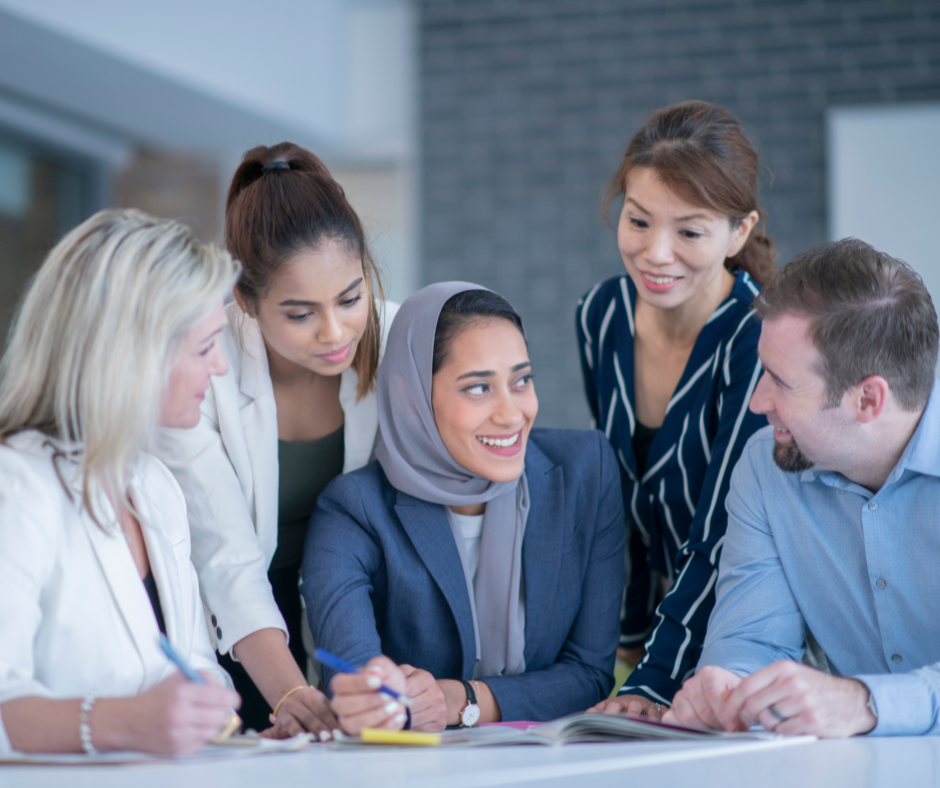 Image is of people of varying ethnicities working together at table