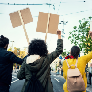 Three people marching and protesting for a social injustice holding signs and fist in air